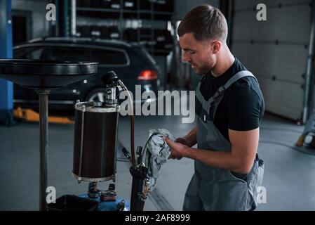 Serviceman cleans instruments. Male mechanic use special device to repair broken automobile in garage Stock Photo
