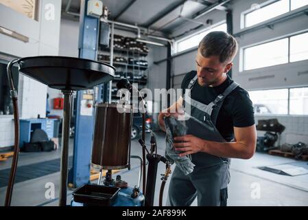 Daylight goes through the glass of doors. Male mechanic use special device to repair broken automobile in garage Stock Photo