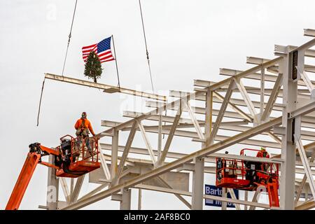 Detroit, Michigan USA - 13 December 2019 - Construction workers raise a flag and a Christmas tree on the last piece of structural steel to be placed on Fiat Chrysler's new automobile assembly plant. It is the first new assembly plant to be built in Detroit in 30 years. Credit: Jim West/Alamy Live News Stock Photo