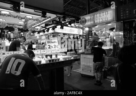 Monochrome image of market stalls selling various drinks and produce within the Mercado de La Boquerioa in Barcelona. Stock Photo