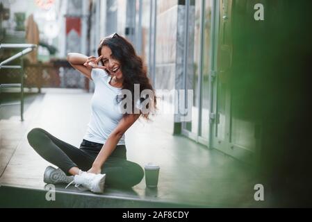 Hello there. Beautiful woman with curly black hair have good time in the city at daytime Stock Photo