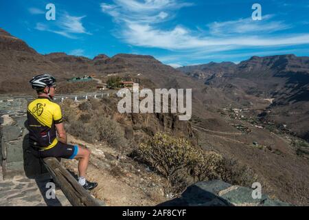 Cyclist enjoying the view from Mirador de Ayagaures, looking down on the town, GC-503, Ayagaures, Gran Canaria, Spain Stock Photo