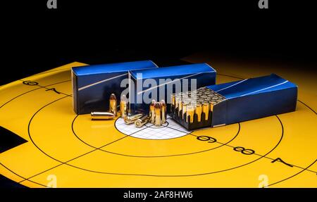 Cartridges in a blue box on a background of a yellow target. 9 mm cartridges for firearms. Stock Photo