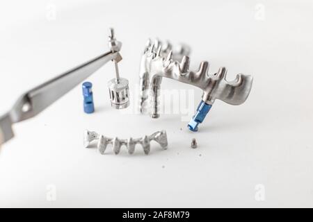 Close-up studio shot on milled metal frame for dental implants on the white background. Concept of new technologies in dental prosthetics Stock Photo
