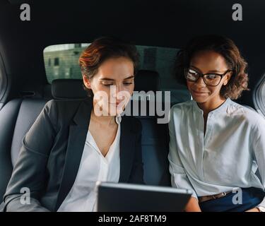 Two business people using digital tablet in taxi Stock Photo