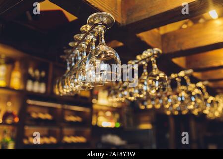 Group of empty wine glasses hanging from metal beams in a bar Stock Photo