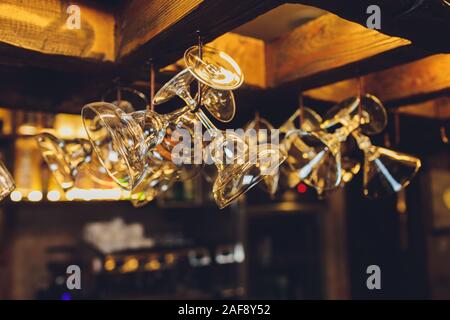 Group of empty wine glasses hanging from metal beams in a bar Stock Photo