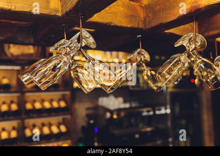 Group of empty wine glasses hanging from metal beams in a bar Stock Photo
