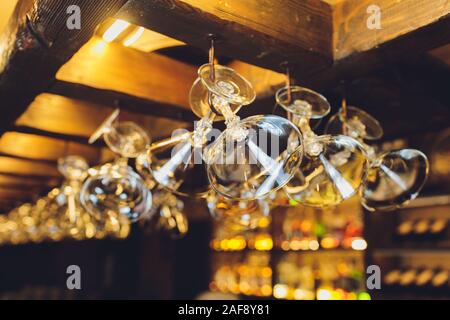 Group of empty wine glasses hanging from metal beams in a bar Stock Photo