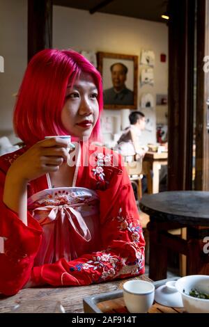 A fashionable young Chinese woman drinking tea and wearing a traditional Chinese tunic Stock Photo