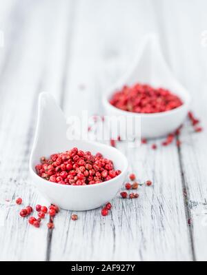 Pink Peppercorns on an old wooden table as detailed close-up shot; selective focus Stock Photo