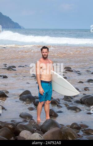 A young male surfer on a Pacific coast beach in El Salvador, Central America Stock Photo