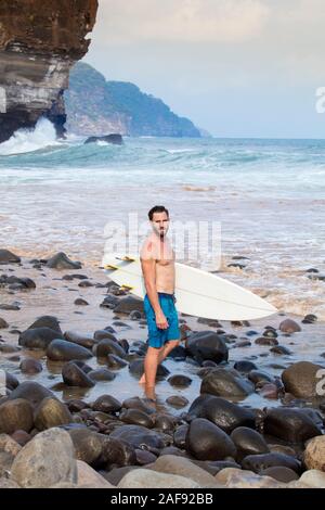 A young male surfer on a Pacific coast beach in El Salvador, Central America Stock Photo