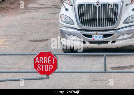 Truck stopped behind bilingual Arret / Stop sign in Blanc-Sablon in Quebec, Canada. Stock Photo