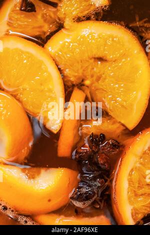 Making hot alcoholic mulled wine with oranges and spices. Christmas beverages boil in the metal pan. Glintwine from rose wine with citrus, cloves Stock Photo