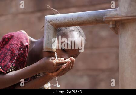Couple of Black African Children Drinking Water from tap, Human Rights, Poverty, Climate Change Stock Photo