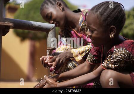 Amazing African school children girls drinking pure water from pump - World Water Day Stock Photo