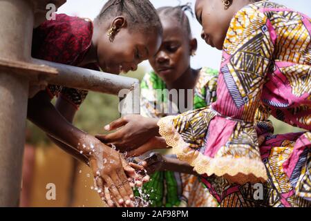 Gorgeous African Girls Washing Hands under Water Tap Outdoors Stock Photo