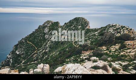 Huge cliff covered with vegetation and Mediterranean Sea cloudy sky photo taken on top of Penon de ifach Natural Park, no people. Beautiful landscape Stock Photo