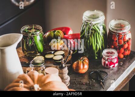 Autumn vegetable pickling and canning. Ingredients for cooking and glass jars with homemade vegetables preserves on concrete kitchen counter. Healthy Stock Photo
