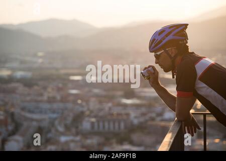 Adventure male Vloger Using Action Camera Outdoor. A male cyclist blogger shoots video on an action camera at sunset. Tourist Caucasian guy uses a Stock Photo