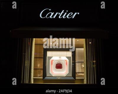 VIENNA, AUSTRIA - NOVEMBER 6, 2019: Cartier logo on their main shop for Vienna with a showcase showing a bag. Cartier is a French luxury goods conglom