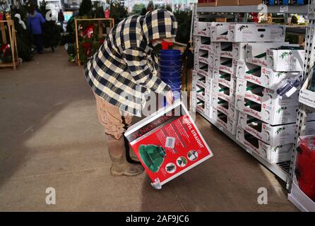 Cromwell, CT USA. Dec 2019. White bearded elderly man in plaid coat looking at new Christmas tree stands in box. Stock Photo