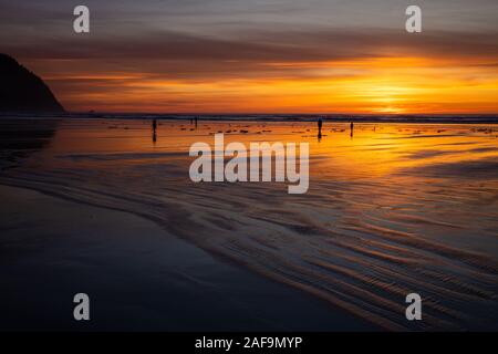 People walking along the beach at sunset in Seaside, Oregon Stock Photo