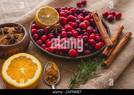 Cranberries on a plate with some ingredients. Lemon, rosemary, anise, cinnamon close up on rustic background Stock Photo