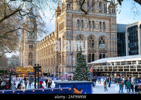 People skating on an artificial ice rink around a christmas tree outside The Natural History Museum, Cromwell Road, London, England Stock Photo
