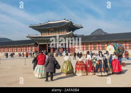 Seoul, South Korea - November 28th, 2019: Tourists wearing traditional Korean Hanbok dress and visiting the Gyeongbokgung palace on a sunny winter day Stock Photo