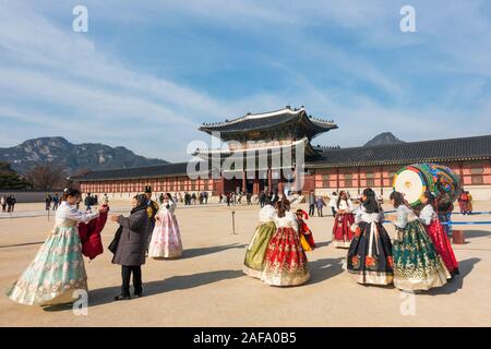 Seoul, South Korea - November 28th, 2019: Tourists wearing traditional Korean Hanbok dress and visiting the Gyeongbokgung palace on a sunny winter day Stock Photo