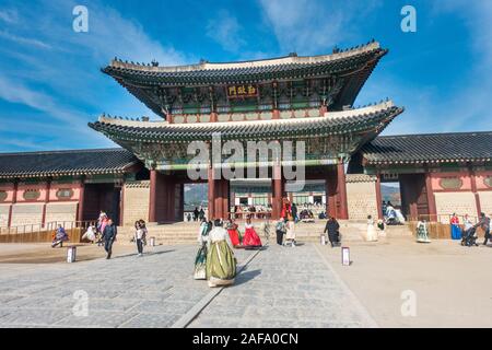 Seoul, South Korea - November 28th, 2019: Tourists wearing traditional Korean Hanbok dress and visiting the Gyeongbokgung palace on a sunny winter day