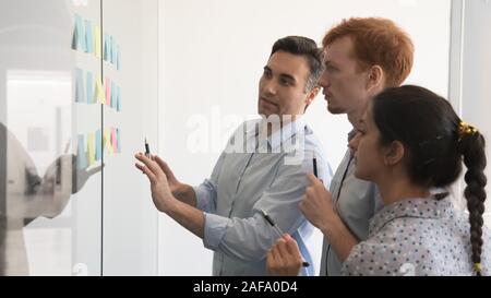 Diverse specialist working together in boardroom using post-it notes Stock Photo