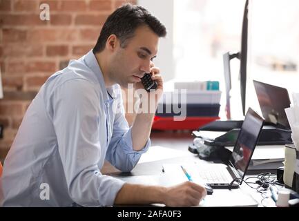 Serious businessman talking on phone having busy working day Stock Photo