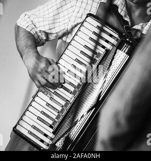 Accordionist plays vintage accordion. Retro stylized square black and white photo Stock Photo