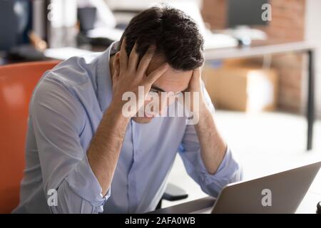 Businessman sitting at desk near computer having problems feels stressed Stock Photo