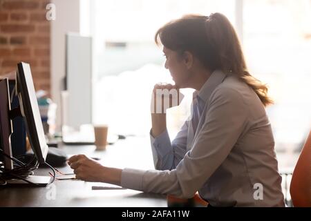 Thoughtful middle aged female employee sitting in workplace feels stressed Stock Photo