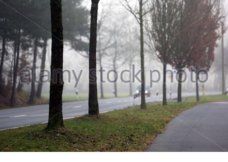 A misty morning in Franconia, Germany as a car travels down the road. Stock Photo