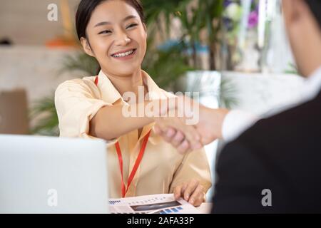 Portrait young Asian woman interviewer and interviewee shaking hands for a job interview .Business people handshake in modern office. Greeting deal co Stock Photo