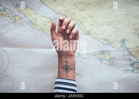 Compass tattoo on sailor ankle with nautical chart in background Stock Photo