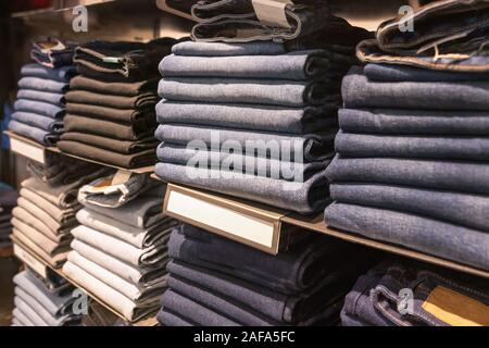Jeans of different colors, textures and shades lie in neat piles on the window counter of the brand fashion store. Stock Photo