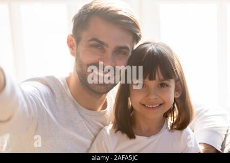 Head shot portrait of smiling father with daughter taking selfie Stock Photo