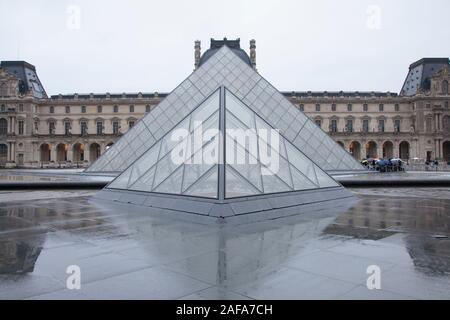 A wet winter morning outside the famous glass pyramid entrance to the Louvre Gallery and Museum in Paris Stock Photo