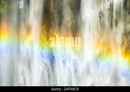 (Selective focus) Close-up view of the Tumpak Sewu Waterfalls with a beautiful rainbow formed by refraction of light in water droplets. Stock Photo