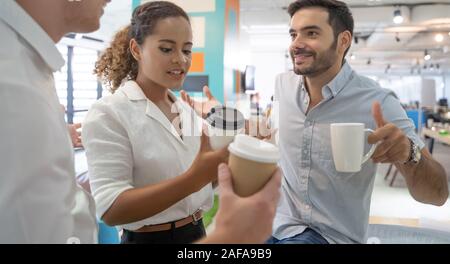 Business people talking and holding cups of coffee .Group of coworkers having a coffee break in office. Stock Photo