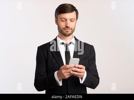 Man In Suit Using Phone Texting With Colleagues, White Background Stock Photo