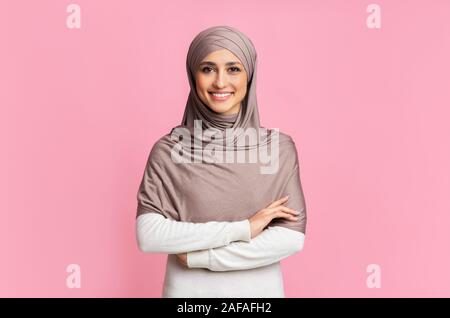 Portrait of happy arab girl in hijab over pink studio background Stock Photo