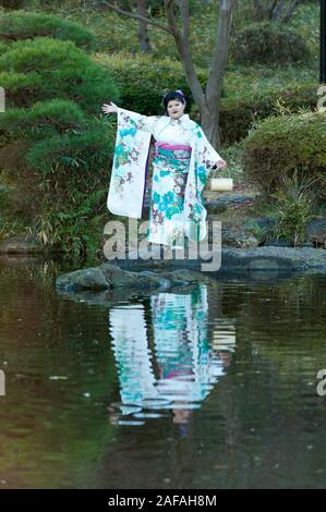 Beautiful Japanese teenager wearing traditional kimono standing looking forward with arms outstretched celebrating the Coming of Age Day in Fuji City, Stock Photo