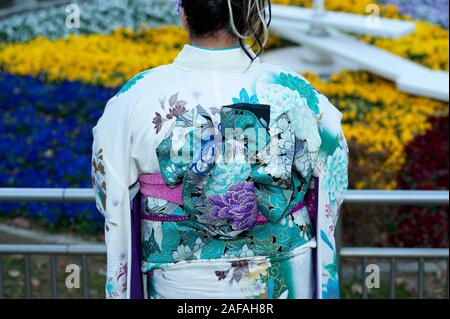 Beautiful Japanese teenager back wearing traditional kimono celebrating the Coming of Age Day in Fuji City, Japan. Background with defocused colorful Stock Photo